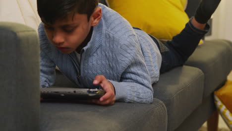 Young-Boy-Lying-On-Sofa-At-Home-Playing-Game-Or-Streaming-Onto-Handheld-Gaming-Device-4