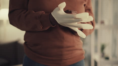 african american woman puts on white rubber glove at home