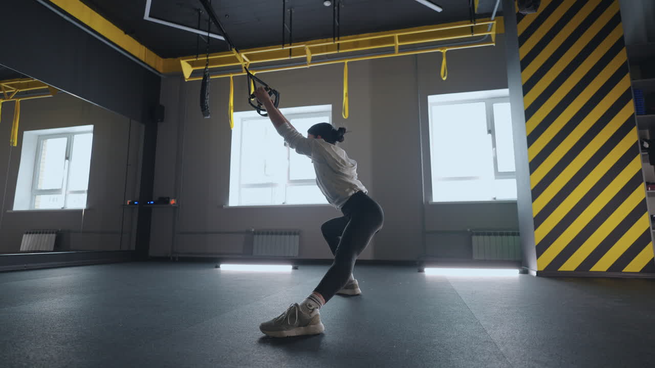 여자 는 체육관 에서 체육 반지 를 사용 하여 스트레칭 운동 을 하고 있다