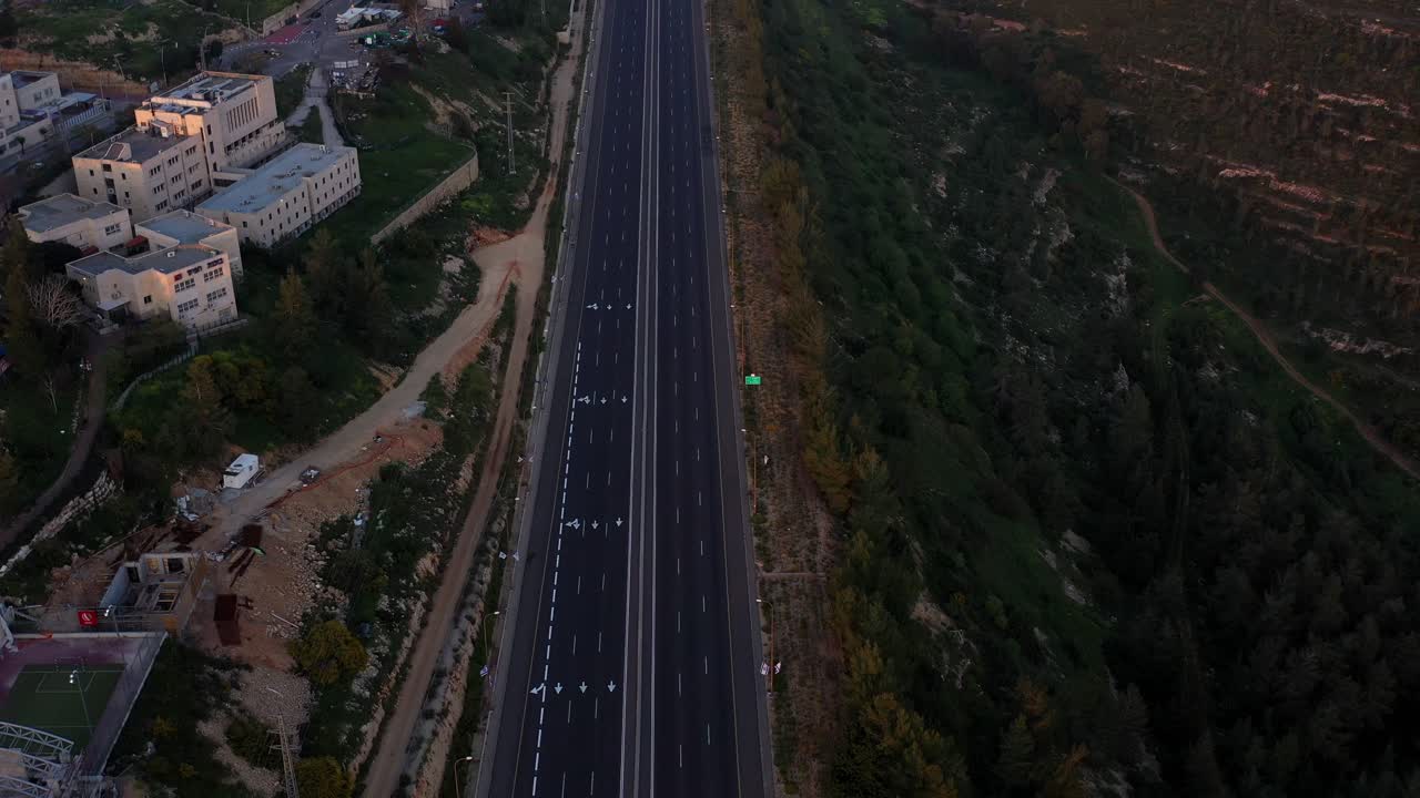 Aerial View of an Empty Highway Between Urban Area and Green Hills