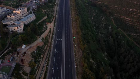 aerial view of an empty highway between urban area and green hills