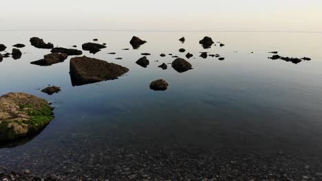 aerial low flying over calm serene tranquil waters with rocks poking through