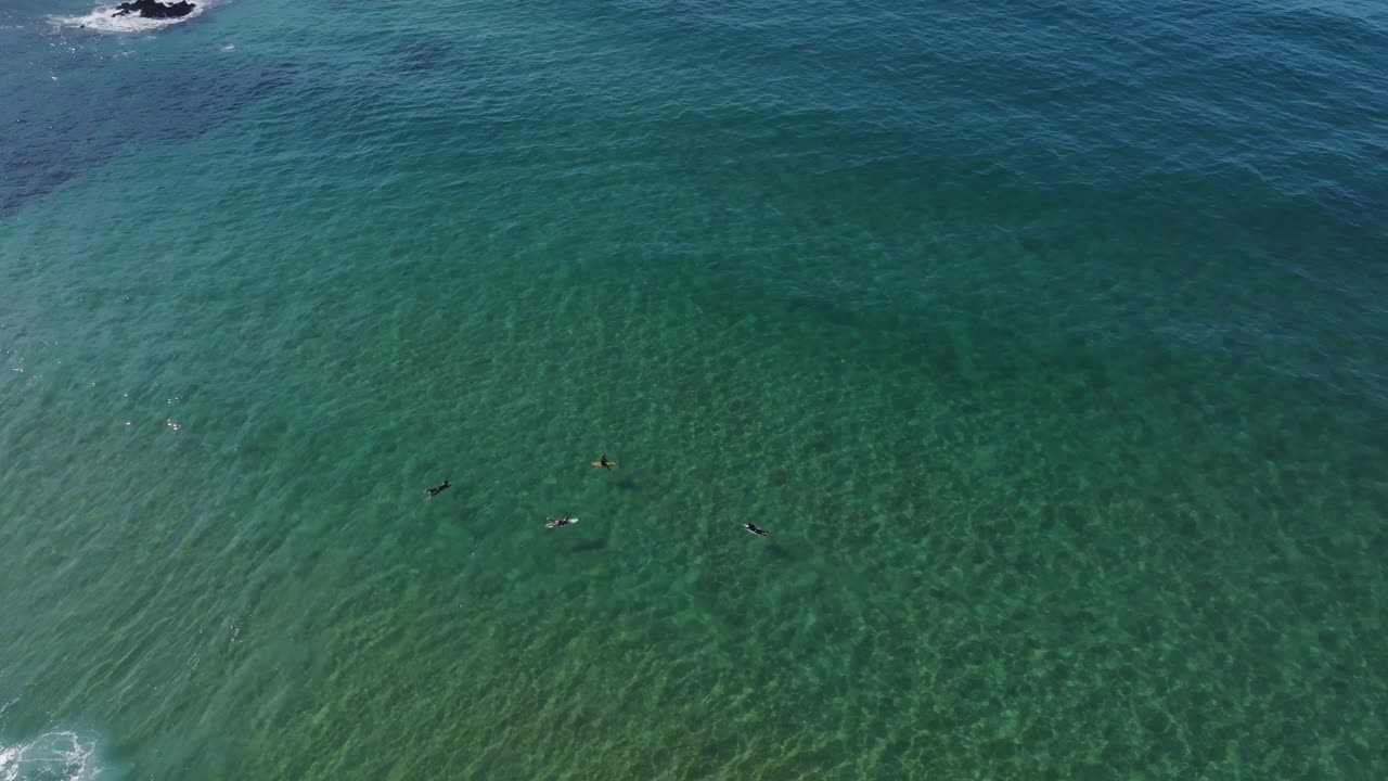 Aerial view of some surfers waiting for a swell of waves to arrive in the beautiful coastline of Portugal