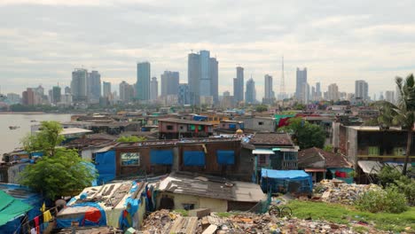 views of slums on the shores of mumbai, india against the backdrop of skyscrapers under construction