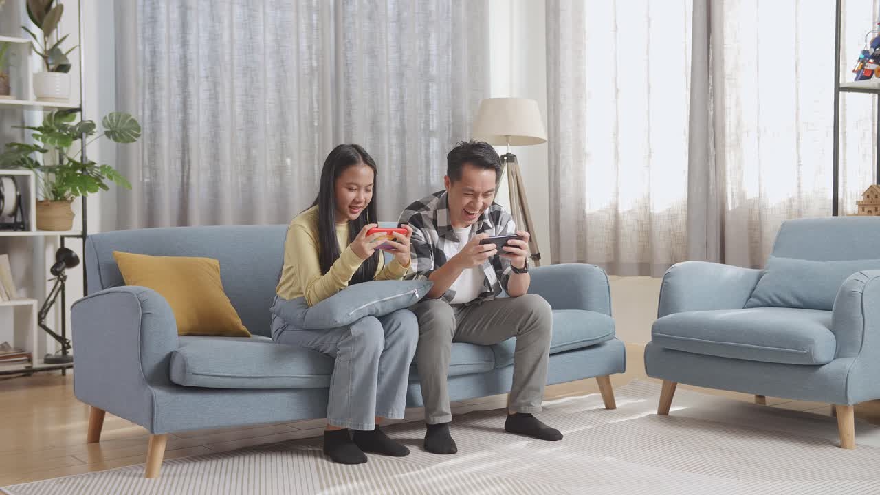 커플 이 소파 에서 모바일 게임 을 하고 있다