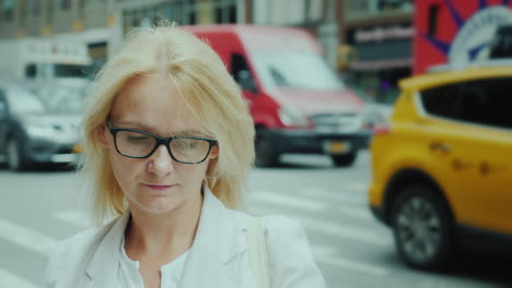 Atractiva-Mujer-Con-Gafas-Está-Mirando-La-Pantalla-De-Un-Teléfono-Inteligente-En-El-Fondo-Son-Altos-Buil