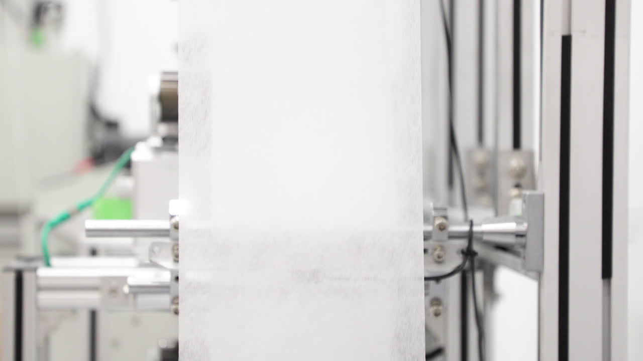 생산 라인의 의료용 마스크용 폴리프로필렌 부직포 - 코로나 바이러스 보호 - 근접 촬영, 느린 동작