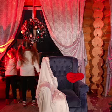 happy little girls saw santa through the window. christmas tree in the living-room. family waiting for santa claus at christmas night