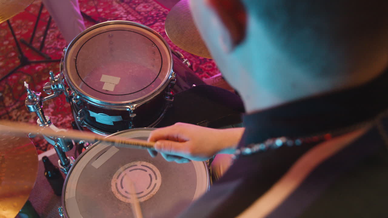 녹음 스튜디오에서 밴드 리허설 중에 드럼을 연주하는 알아볼 수 없는 활기찬 음악가