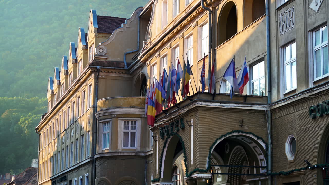 View of a classic building in old town centre with multiple flags on it in Brasov, Romania