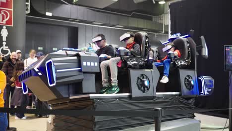 family riding on a cool virtual rollercoaster machine with vr goggles on a convention at lgx event in luxembourg. father having fun with his boys testing new games and entertainment technology