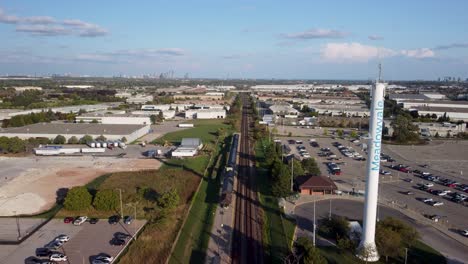 push in drone view on train tracks in an industrial area along with road traffic