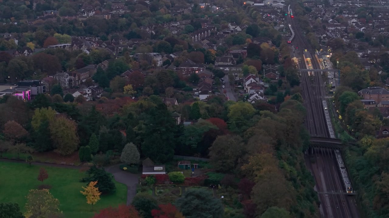 Discesa con vista aerea verso un treno che viaggia sulla linea ferroviaria di Croydon attraverso un quartiere residenziale suburbano