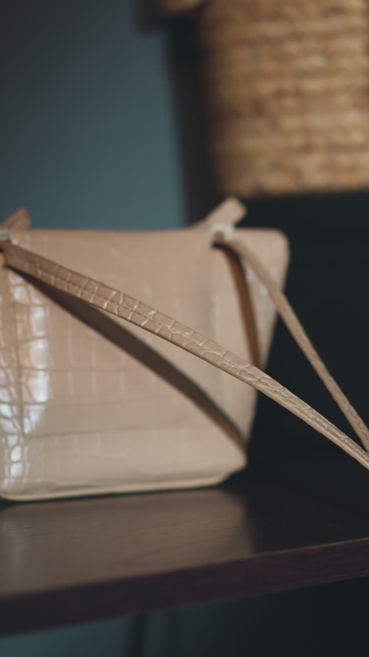 Woman with red manicure puts beige ladies handbag on shelf in hallway. Tired young person prepares to rest at home after hard day at work closeup