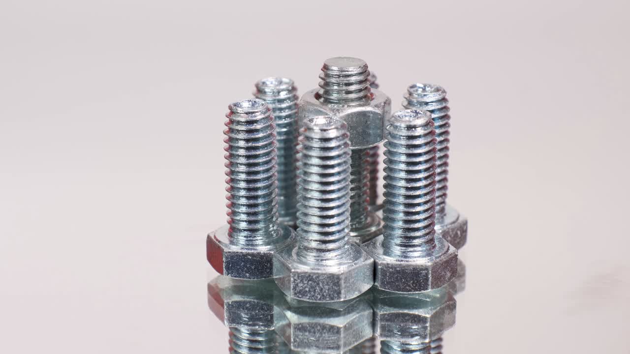 grupo giratorio de tornillos metálicos galvanizados de primer plano. pernos de acero inoxidable aislados en el fondo reflectante del espejo.