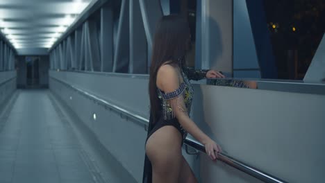junge frau in einem glitzernden kleid an einer überführung in der nacht mit blick auf die stadt