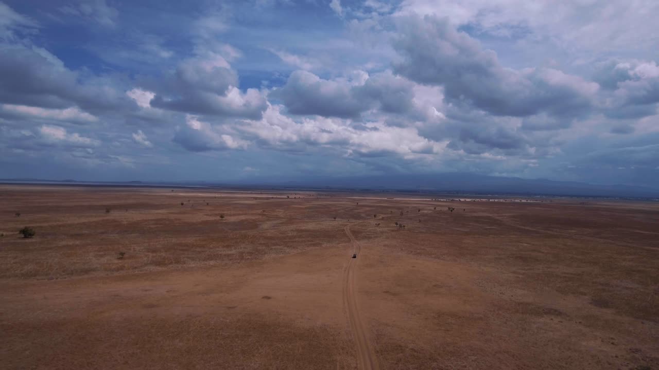 Droneoptagelse af en SUV, der kører gennem afrikansk savanne. Rangers sporer krybskytter. Turister på safari.