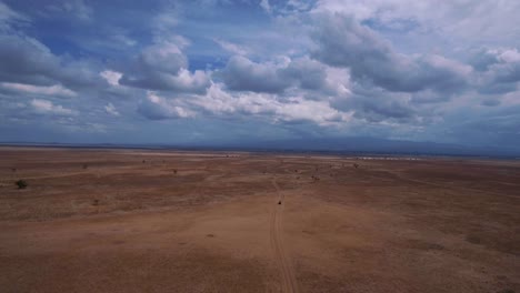 drone shot of suv driving through african savannah. rangers tracking poachers. tourists on safari