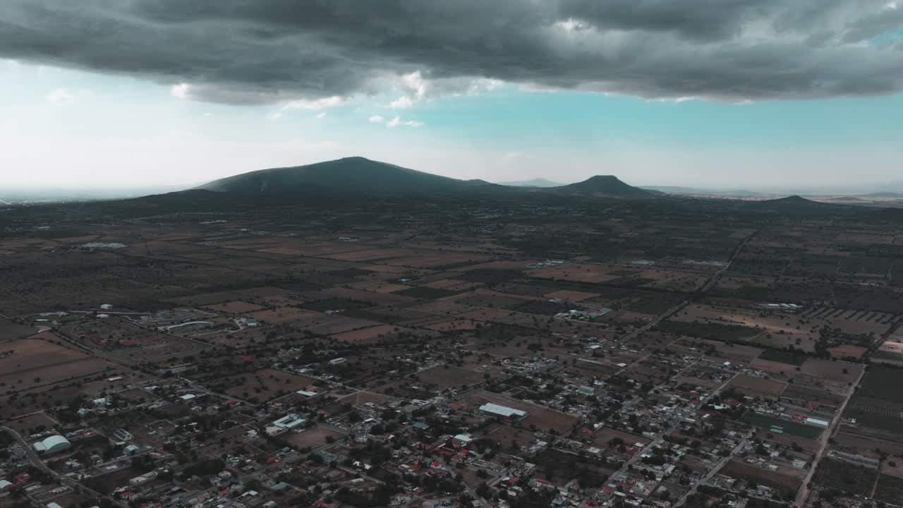 Vídeo de drone sobre Nopaltepec, México, apresentando vistas da cidade, montanhas distantes e nuvens escuras em um cenário rural