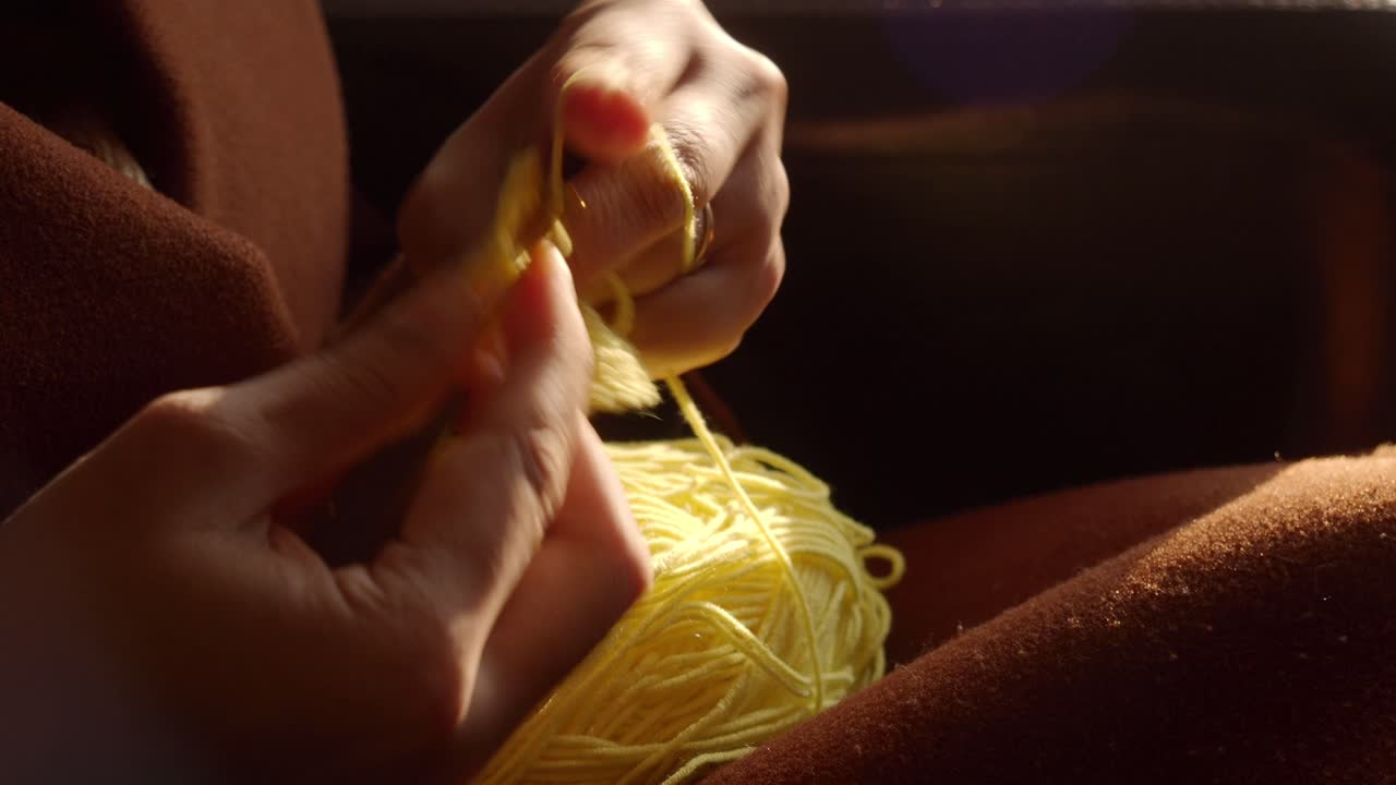 노란색 가닥으로 뜨개질 하는 여자