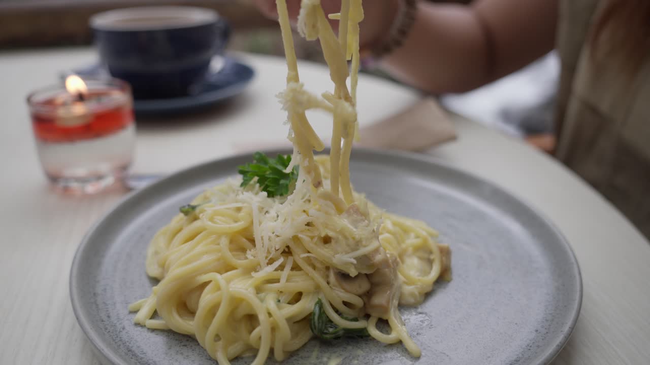 Girl savoring pasta with a candle on the table