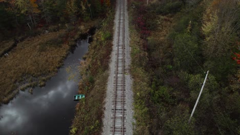 aerial tilt up of old railway track near autumn forest and electric line