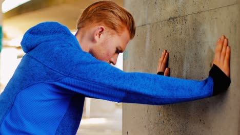 Young-man-pushing-against-wall-while-exercising,-4K-4k