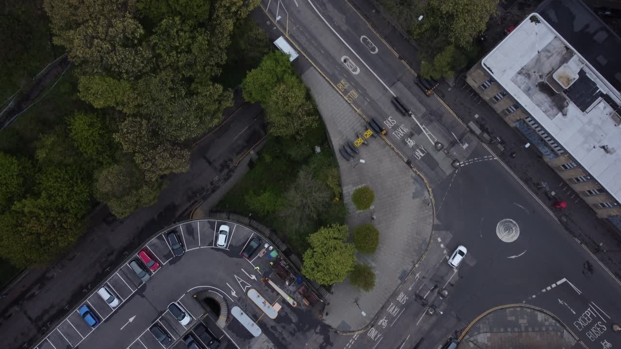Drone view of Edinburgh showing historic castle, quiet curved road, city buildings, distant hills, and peaceful sky during evening light, capturing charm and calm of Scottish capital