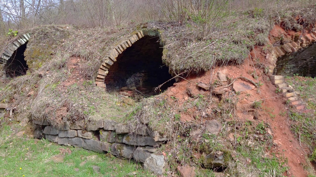 Historical coke oven tunnel built into red hillside with stone foundation