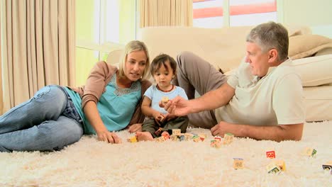 padres jugando con el bebé acostado en una alfombra
