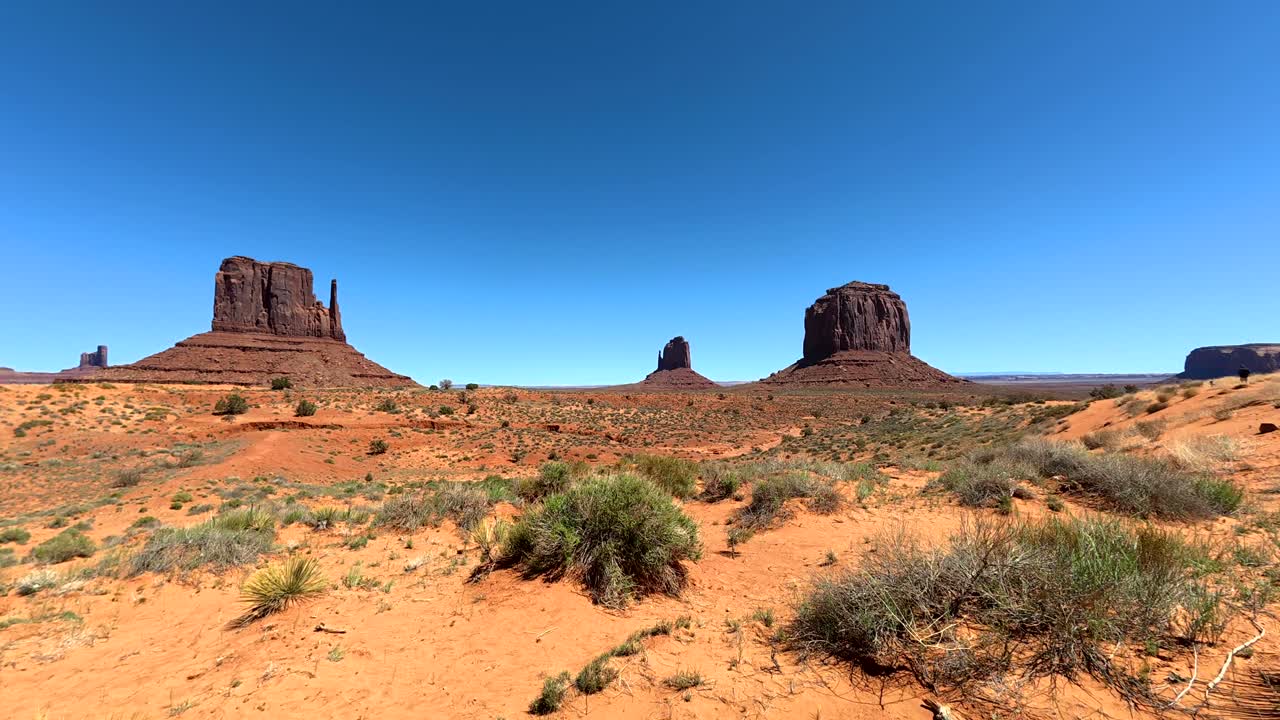Caminando por arena roja en Monument Valley con mesas icónicas.