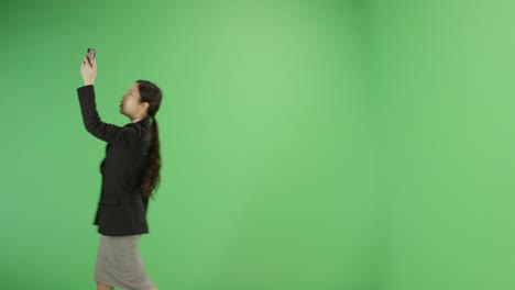 mujer de negocios tratando de encontrar señal de teléfono en pantalla verde