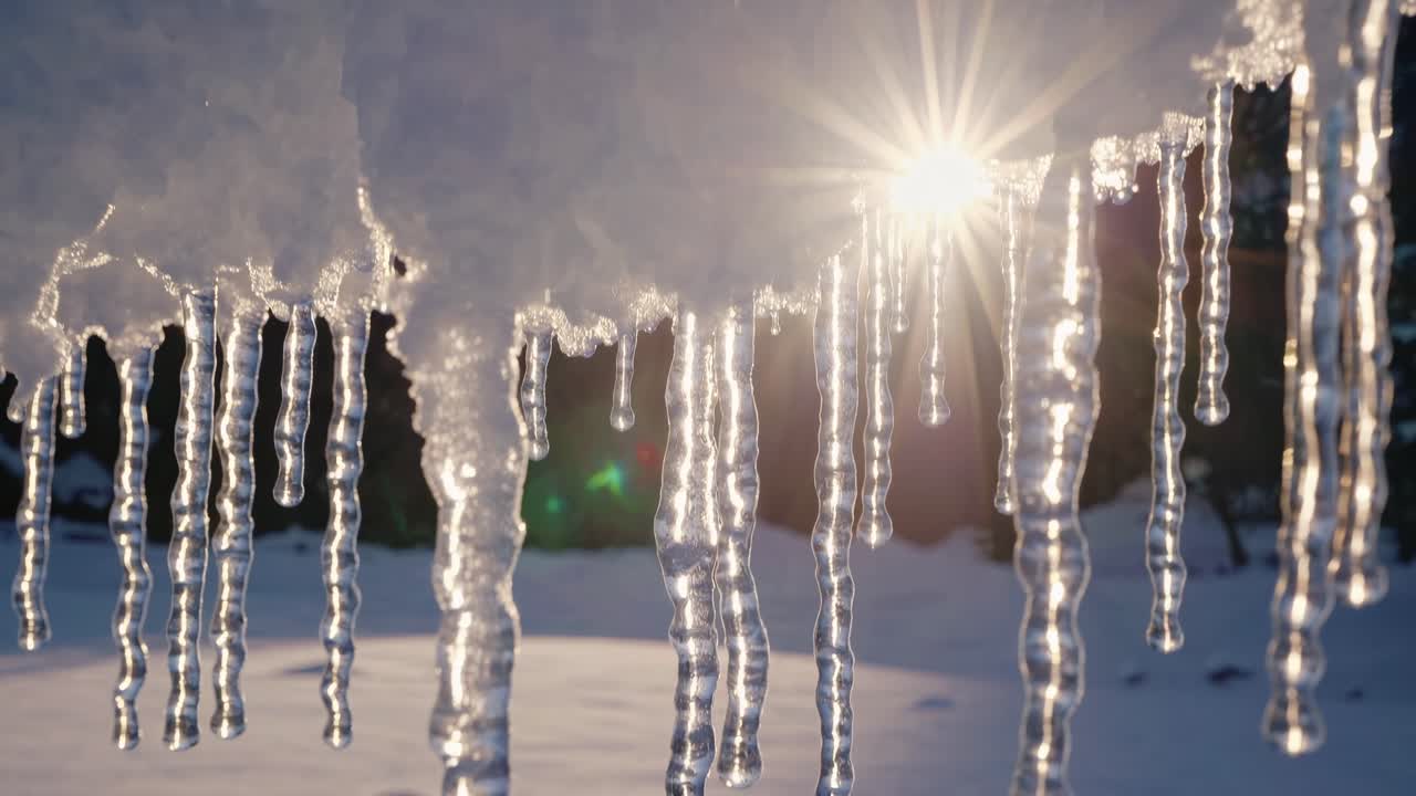 Close-up video of icicles hanging from a snowy roof, captured from a low angle