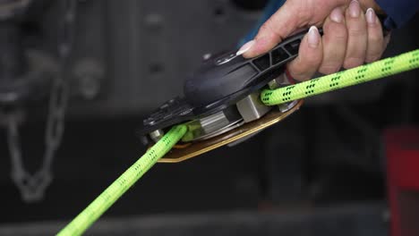 Woman-sliding-rope-through-safety-pulley-in-closeup