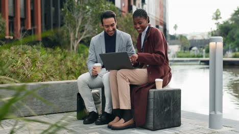 two business people working together on a laptop in a modern urban park setting.