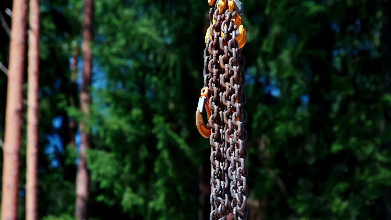 Heavy chains and a tackle hang loose, waiting to be needed for lifting work