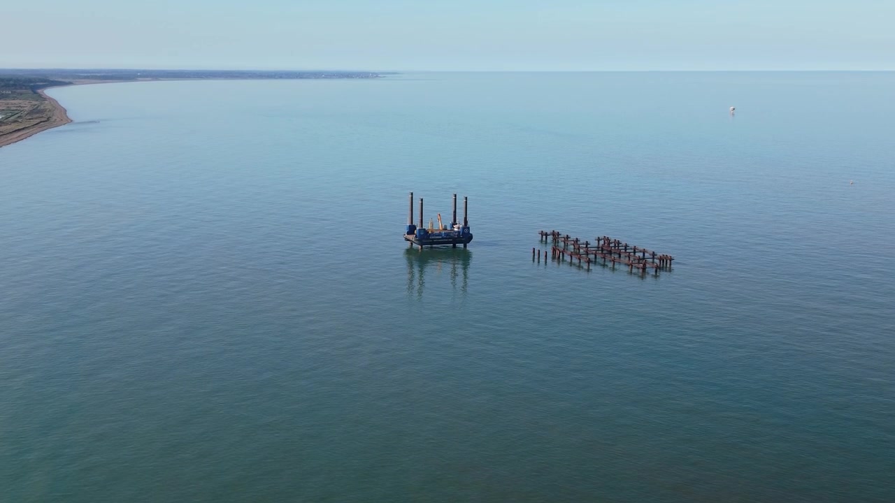 Aerial view of jackup barge and offshore construction pilings near Suffolk coastline