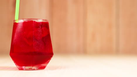 bebida roja en vaso con paja verde que se agita