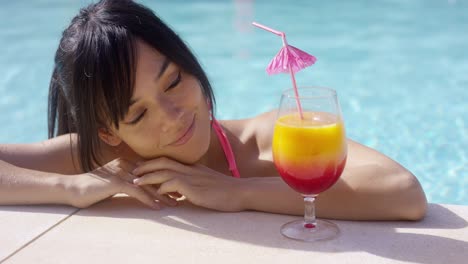 Happy-young-woman-eyeing-a-large-tropical-cocktail