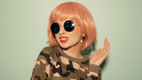 woman in pink wig, sunglasses, and camouflage outfit