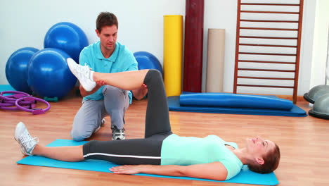 entrenador ayudando a su cliente a doblar la rodilla