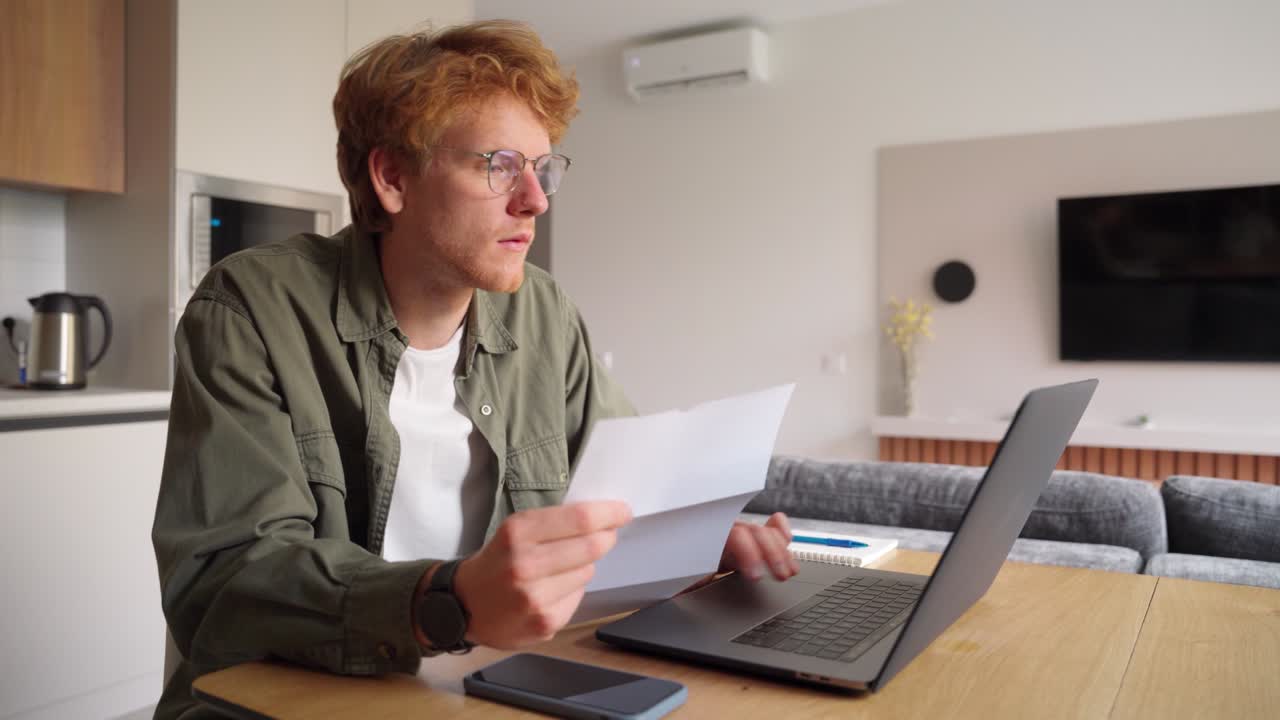 Ginger irlandese freelance che lavora con laptop e documenti in ufficio a casa