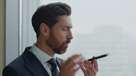 closeup annoyed businessman recording voice message on speakerphone at office.
