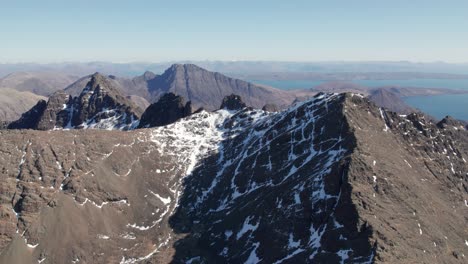 aerial drone panning shot of the cuillin mountains in scotland on a sunny day