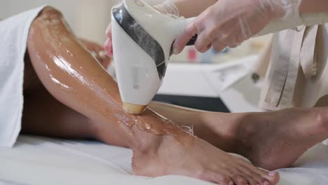 laser epilation and cosmetology in beauty salon. cosmetology, spa and hair removal concept. laser hair removal procedure of female legs. doctor in gloves.