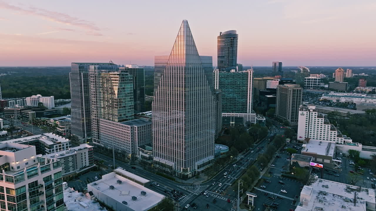 Establishing orbit of sunlight glistening on office buildings in Atlanta with distant skyline and setting sun