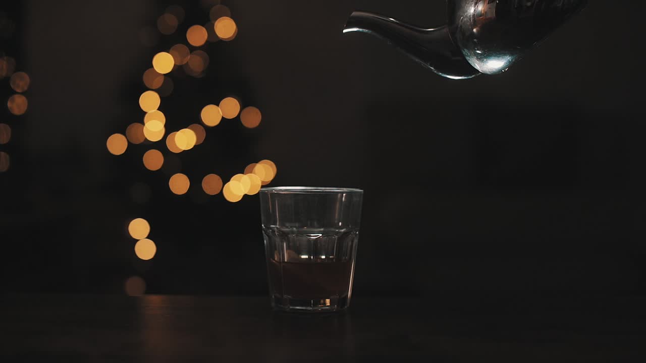 찻주전자로 크리스탈 유리에 뜨거운 물을 붓는다