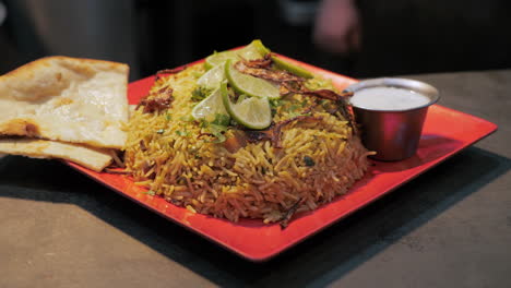 Traditional-Indian-biryani-plated-with-raita-and-naan,-slider-slow-motion-HD