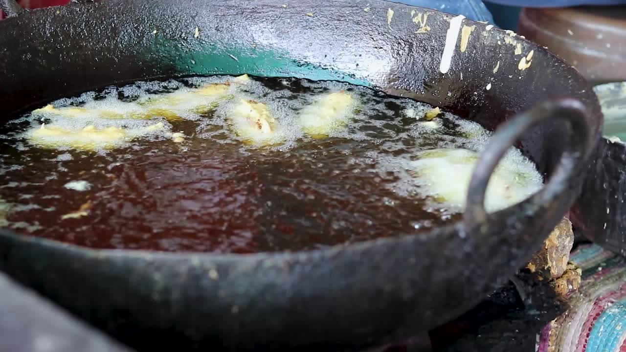 deep frying of big chili at mustered oil at street shop or Mirchi badda local dishes of india at street