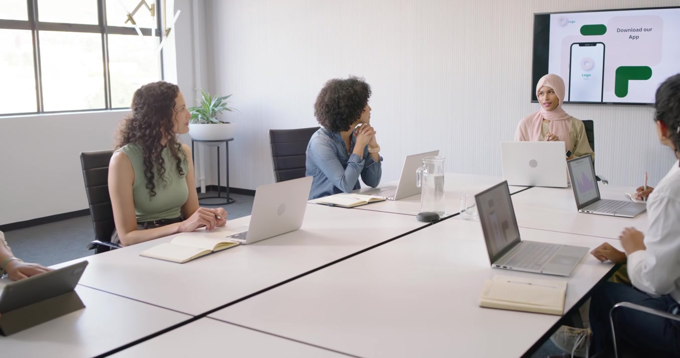 Donna indiana con hijab che entra da destra con un laptop che mostra un mockup di app al tavolo, con spazio per il testo